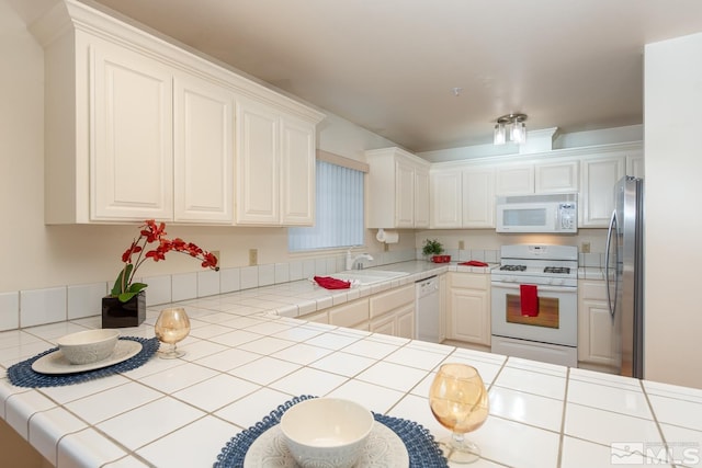 kitchen featuring white cabinetry, sink, tile counters, and white appliances