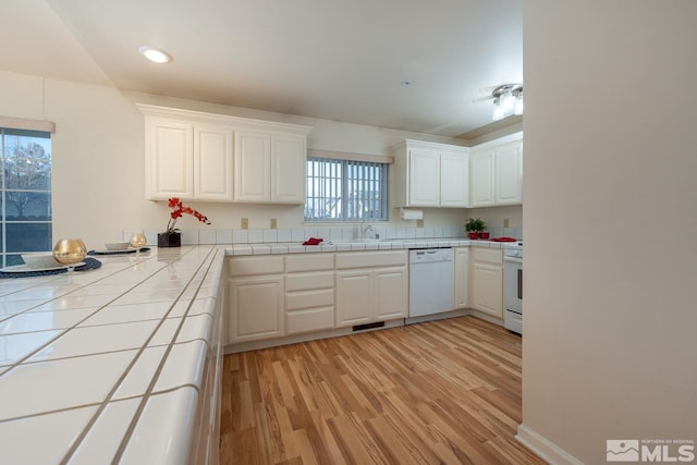 kitchen with tile countertops, white cabinets, white appliances, and light hardwood / wood-style floors