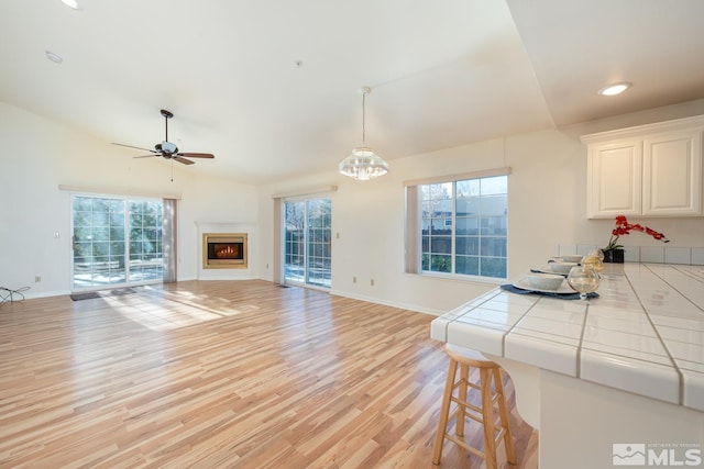 living room featuring lofted ceiling, light hardwood / wood-style floors, and ceiling fan