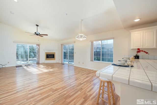 living room with ceiling fan, lofted ceiling, and light wood-type flooring