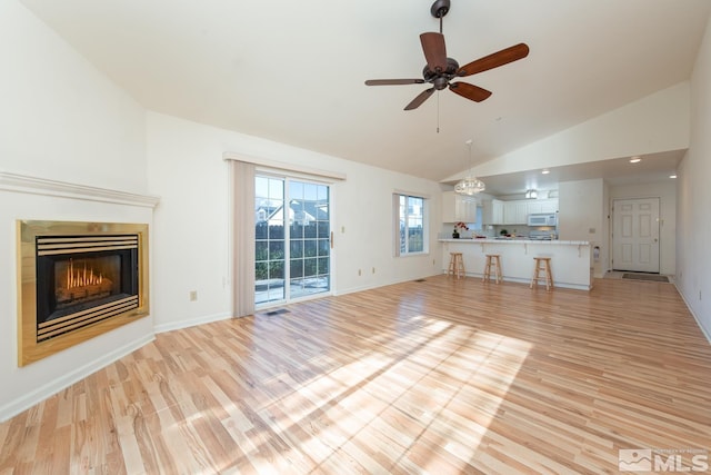 unfurnished living room featuring ceiling fan, high vaulted ceiling, and light wood-type flooring