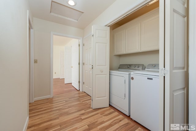 laundry room with washer and dryer, light hardwood / wood-style floors, and cabinets