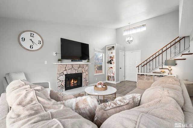 living room with plenty of natural light, high vaulted ceiling, a stone fireplace, and light wood-type flooring