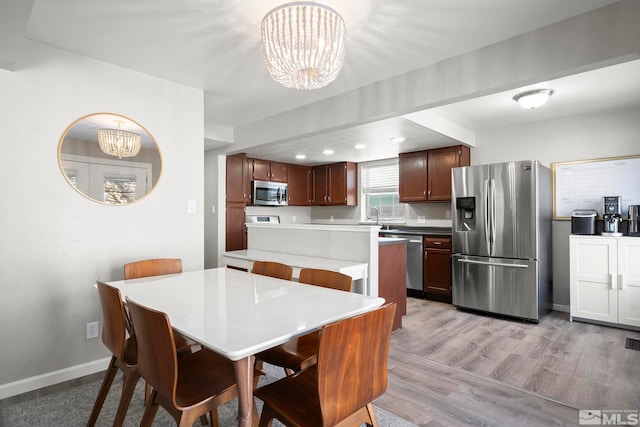 dining area with an inviting chandelier, sink, and light hardwood / wood-style floors