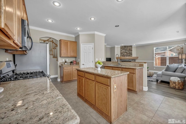 kitchen with crown molding, light stone countertops, a center island, and sink