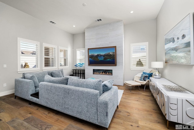 living room featuring plenty of natural light, a fireplace, and light wood-type flooring