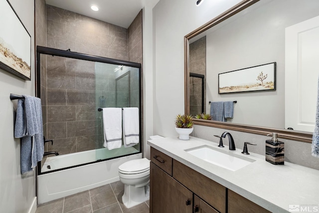 full bathroom featuring tile patterned flooring, vanity, combined bath / shower with glass door, and toilet