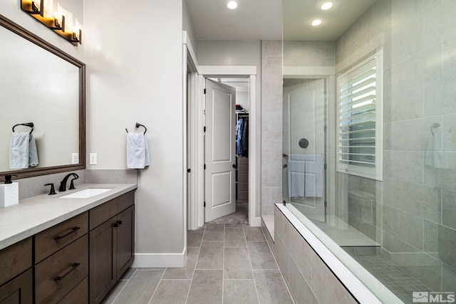 bathroom featuring tiled shower, vanity, and tile patterned flooring