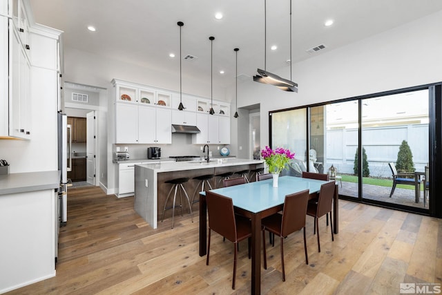 dining space with a towering ceiling, sink, and light wood-type flooring