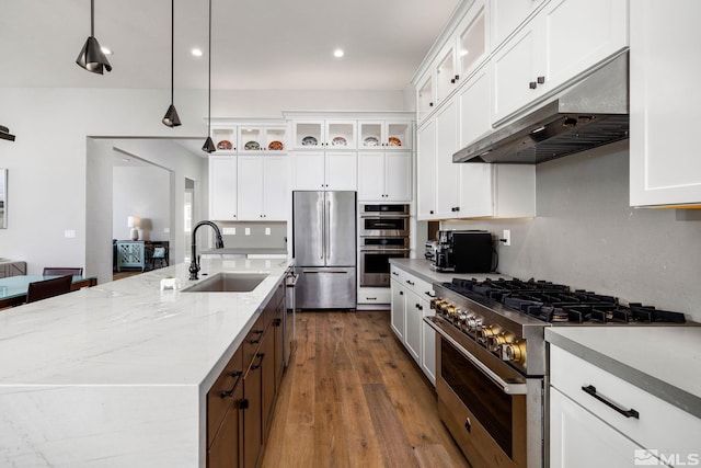 kitchen featuring sink, hanging light fixtures, premium appliances, an island with sink, and white cabinets