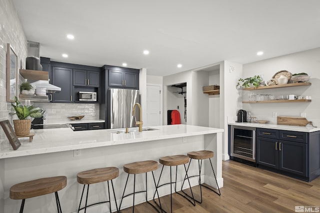 kitchen featuring sink, a breakfast bar, stainless steel appliances, kitchen peninsula, and beverage cooler