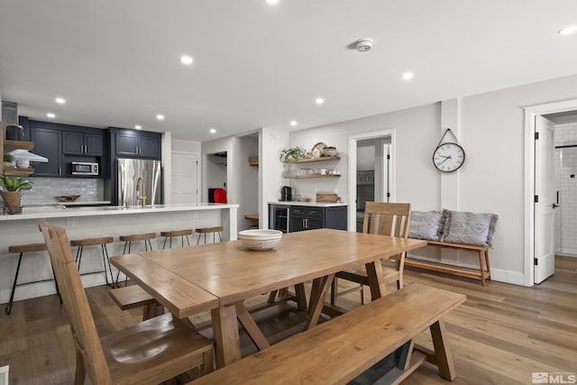 dining room with sink, light hardwood / wood-style floors, and beverage cooler