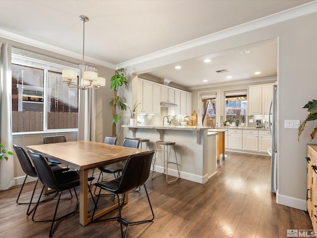 dining area featuring crown molding, dark hardwood / wood-style floors, and an inviting chandelier