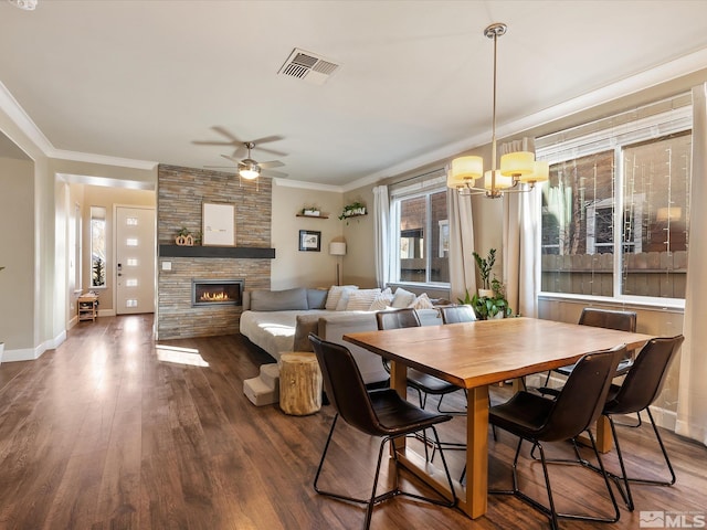 dining area featuring crown molding, a fireplace, dark wood-type flooring, and ceiling fan with notable chandelier