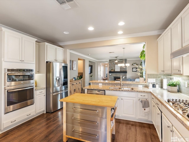 kitchen with sink, butcher block countertops, white cabinetry, appliances with stainless steel finishes, and kitchen peninsula