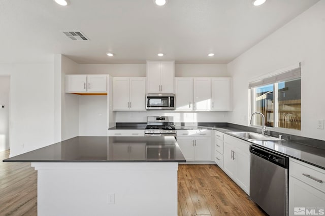 kitchen featuring sink, light hardwood / wood-style flooring, appliances with stainless steel finishes, a kitchen island, and white cabinets