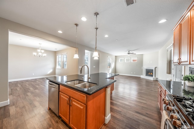 kitchen featuring sink, a center island with sink, dark hardwood / wood-style floors, stainless steel appliances, and ceiling fan with notable chandelier