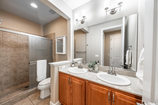 bathroom with tile patterned flooring, vanity, a shower with shower door, and toilet