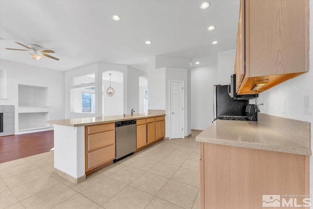 kitchen featuring sink, light tile patterned floors, light brown cabinets, kitchen peninsula, and stainless steel appliances