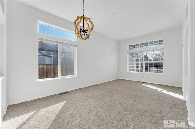 spare room featuring carpet and a notable chandelier