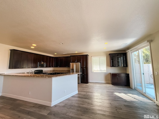 kitchen featuring stainless steel appliances, plenty of natural light, hardwood / wood-style flooring, and dark brown cabinetry