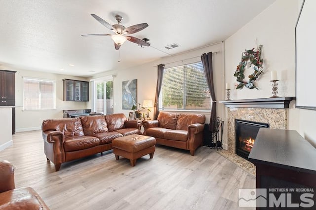 living room with ceiling fan, a premium fireplace, and light hardwood / wood-style floors