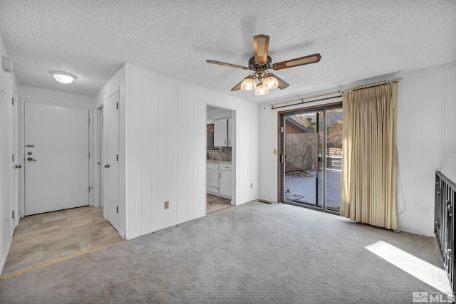 unfurnished living room featuring ceiling fan, light carpet, and a textured ceiling