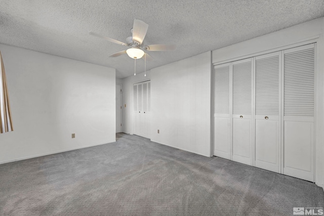 unfurnished bedroom featuring ceiling fan, carpet flooring, a textured ceiling, and two closets