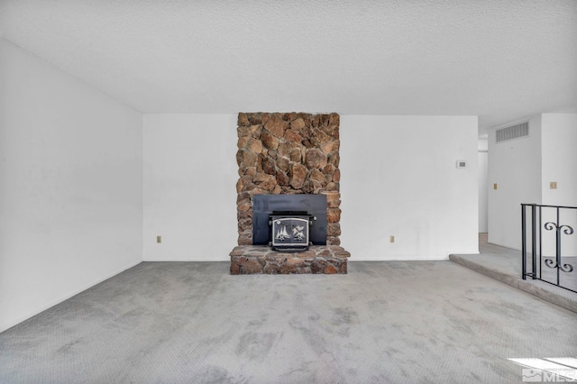 unfurnished living room featuring a wood stove, a textured ceiling, and carpet