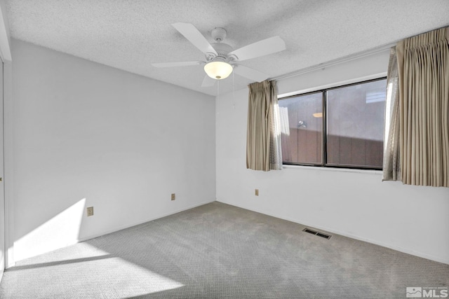 carpeted spare room featuring ceiling fan and a textured ceiling