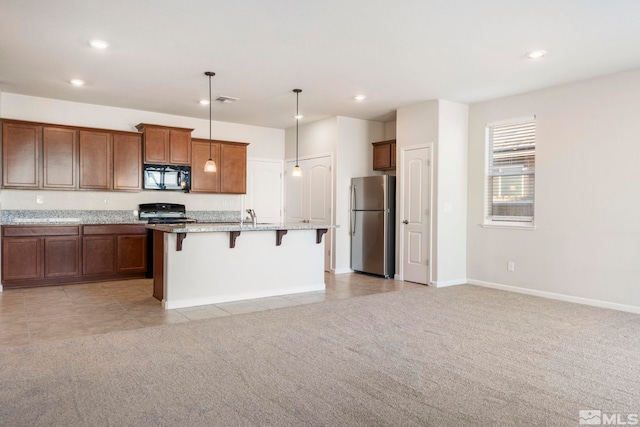 kitchen featuring a kitchen island with sink, hanging light fixtures, stainless steel fridge, and light colored carpet