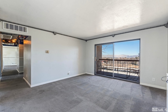 carpeted spare room with a mountain view and a textured ceiling