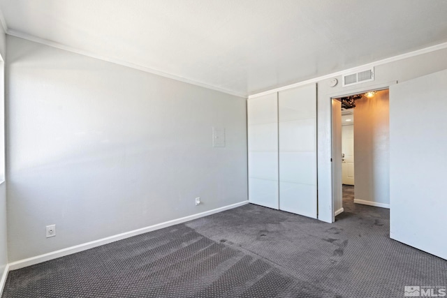 unfurnished bedroom featuring dark carpet and a closet