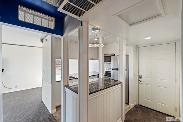 kitchen with stainless steel appliances, white cabinetry, and decorative light fixtures