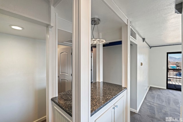 kitchen featuring white cabinetry, dark carpet, a textured ceiling, and dark stone countertops