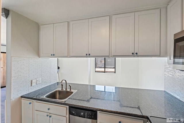 kitchen featuring sink, white cabinetry, dark stone counters, stainless steel appliances, and backsplash