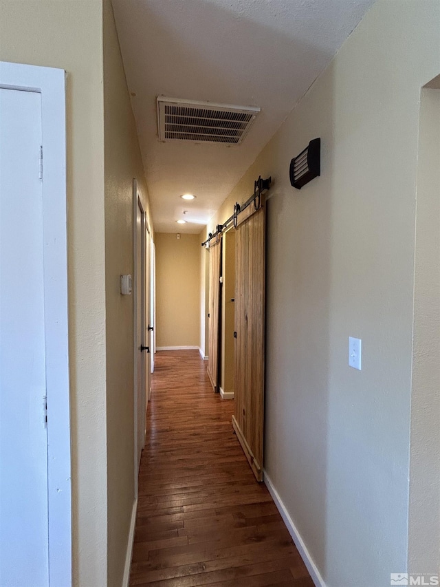 hallway featuring a barn door and dark hardwood / wood-style flooring