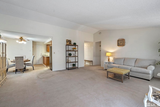 carpeted living room with vaulted ceiling, a textured ceiling, and ceiling fan