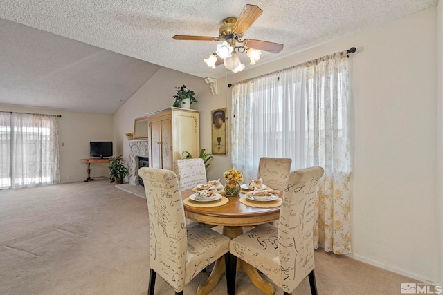 dining room featuring ceiling fan, vaulted ceiling, light colored carpet, and a textured ceiling