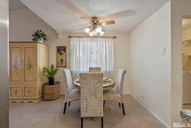 dining area featuring ceiling fan, light colored carpet, and a textured ceiling