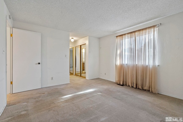 empty room featuring light colored carpet and a textured ceiling