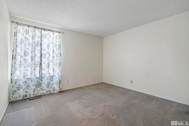 carpeted empty room featuring a textured ceiling