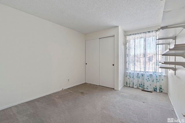 unfurnished bedroom with light colored carpet, a textured ceiling, and a closet