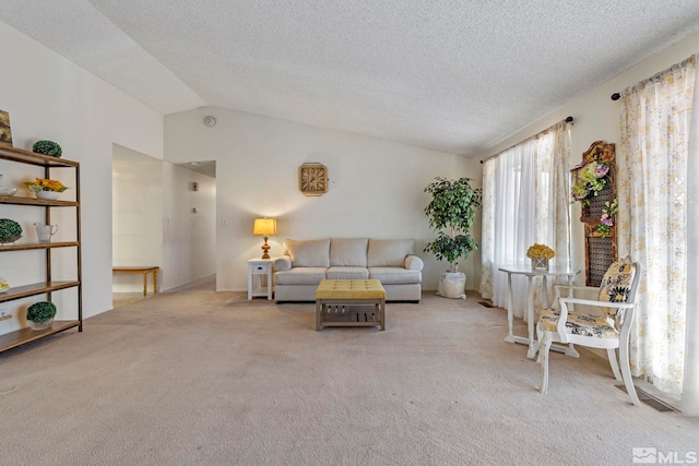 living room featuring vaulted ceiling, light carpet, and a textured ceiling