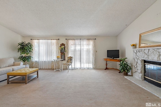 carpeted living room featuring a stone fireplace and a textured ceiling