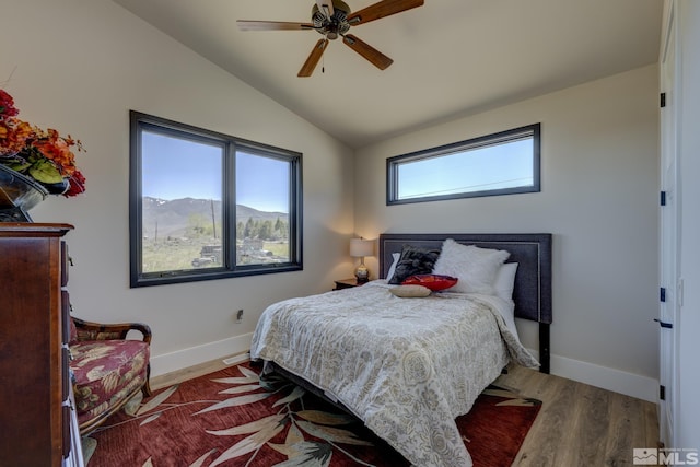 bedroom with hardwood / wood-style flooring, ceiling fan, a mountain view, and vaulted ceiling