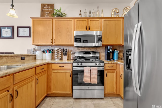 kitchen featuring light stone counters, hanging light fixtures, light tile patterned floors, appliances with stainless steel finishes, and decorative backsplash