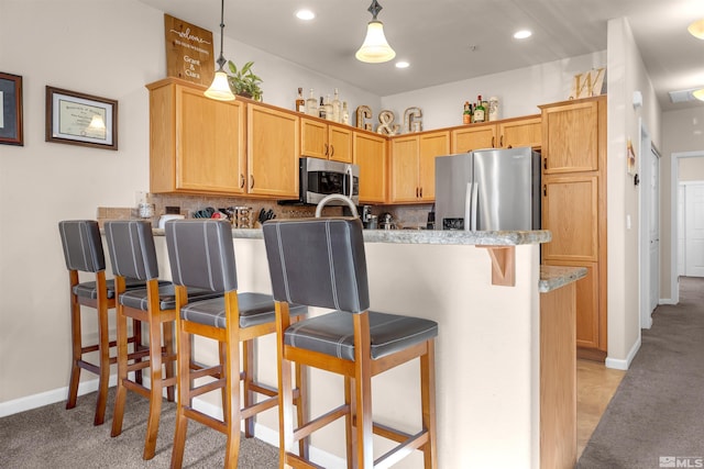 kitchen with tasteful backsplash, appliances with stainless steel finishes, a breakfast bar, and hanging light fixtures