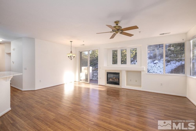 unfurnished living room featuring dark hardwood / wood-style flooring and ceiling fan with notable chandelier