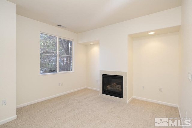 unfurnished living room featuring a tile fireplace and light carpet